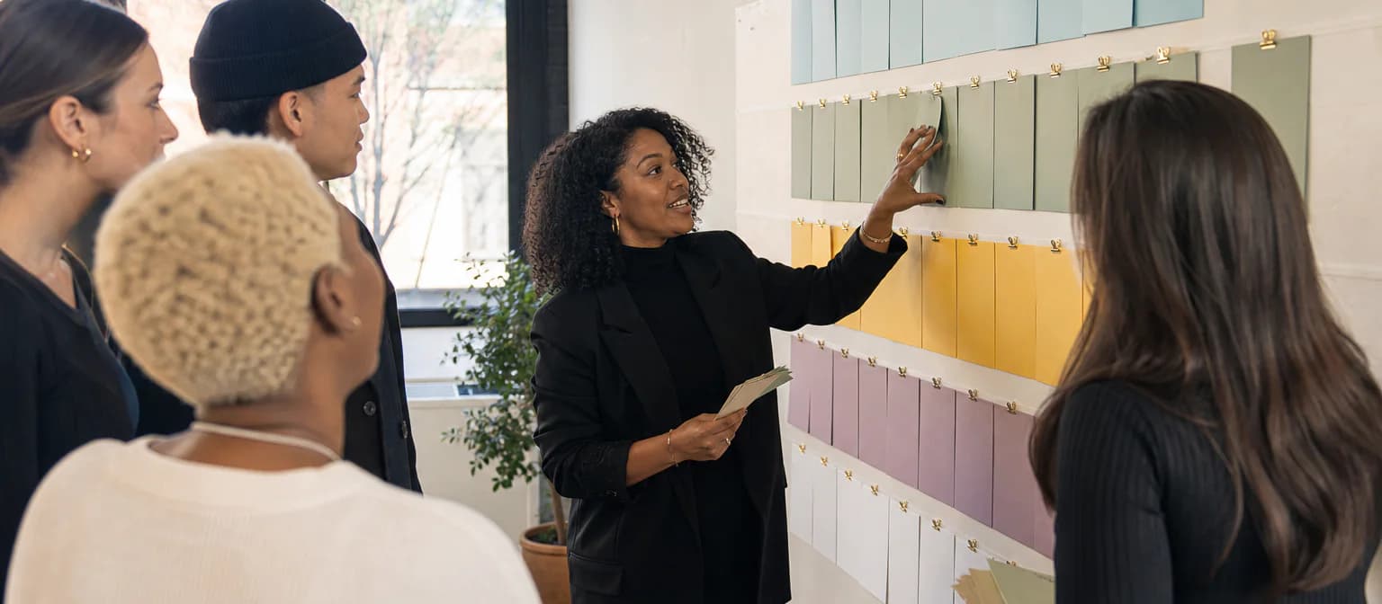 A lead wedding planner guides a diverse team around blank color-coded schedule cards.